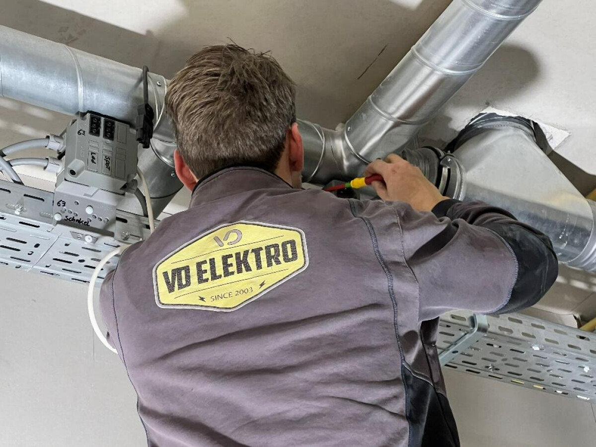 Een medewerker van VD elektro die werkzaam is aan plafondbekabeling. Een medewerker van VD elektro die werkzaam is aan plafondbekabeling.