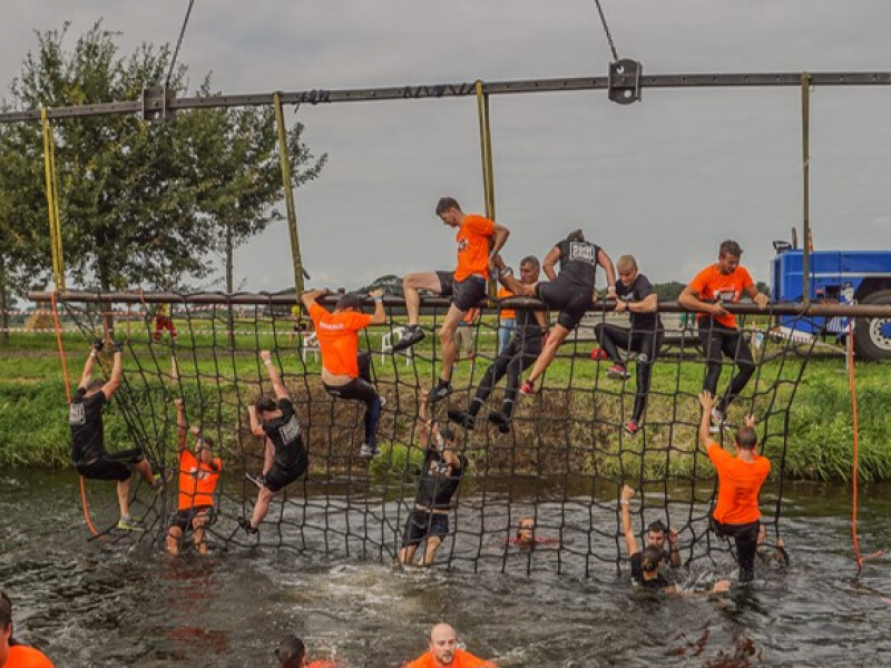 Een groep mensen dat over een obstakel in het water klimt.